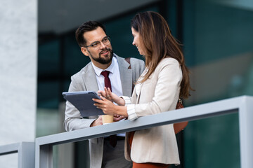 Business people using tablet and talking during coffee break outside office