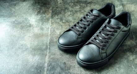 The image features a pair of black leather sneakers on a gray background, which can also be described as black sneakers or simply leather sneakers, and are generally referred to as shoes