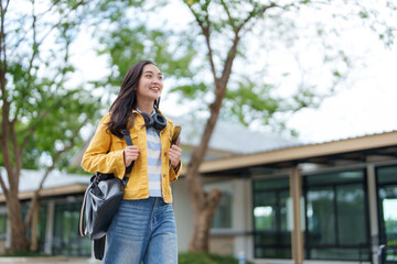 University student walking on campus holding books and smiling