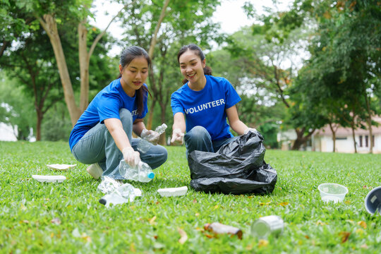 Volunteers collecting trash in park wearing blue shirts
