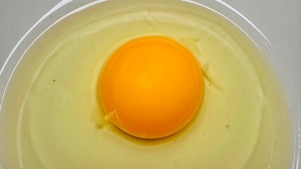 Fresh raw egg yolk in ceramic plate isolated on white background. Raw egg yolk. Cracked egg in a white bowl, ideal for culinary and kitchen themes. Top view.