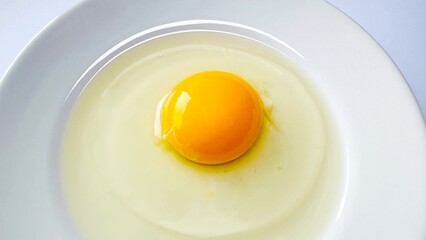 Fresh raw egg yolk in ceramic plate isolated on white background. Raw egg yolk. Cracked egg in a white bowl, ideal for culinary and kitchen themes. Top view.
