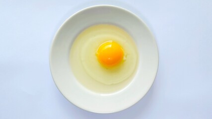 Fresh raw egg yolk in ceramic plate isolated on white background. Raw egg yolk. Cracked egg in a white bowl, ideal for culinary and kitchen themes. Top view.
