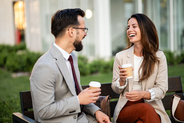 Business people chatting and laughing during coffee break outdoors