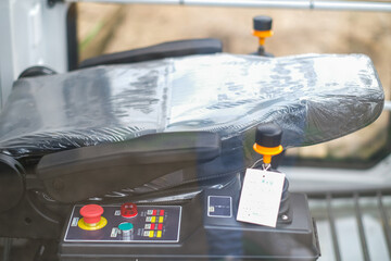 Moscow, Russia, 18.06.2025 New operator seat with plastic wrap and control panel for heavy machinery. Unused equipment interior detail view.