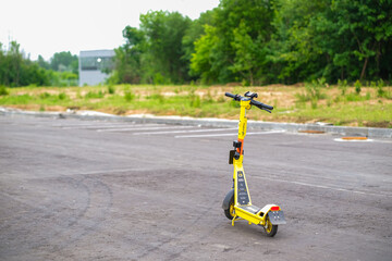 Moscow, Russia, 18.06.2025 Yellow electric kick scooter parked on an empty asphalt road. Eco friendly short distance urban transport or rental service. Public mobility.