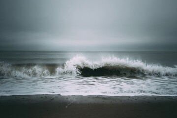 Ocean wave crashing on a grey beach