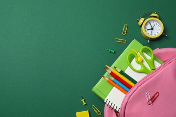 Bright collection of school supplies including pink backpack and stationery on bright green background, perfect for educational and school themes