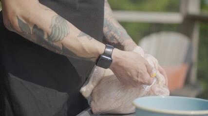 A man is preparing food in a blue bowl. He is wearing a watch and has tattoos on his arm