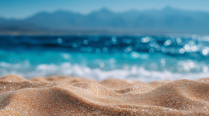 Obraz premium Close-up of beach sand under the sun with out-of-focus turquoise sea sparkling in the background, perfect summer holiday vibe sunlit sand, ocean bokeh, blurry sea, beach texture, c