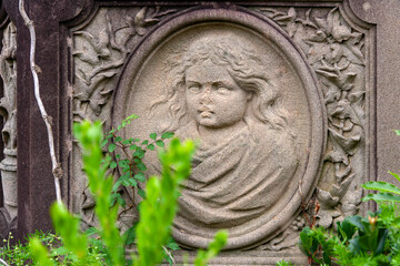 Detail of a tombstone with a carved relief of a child's face, surrounded by floral motifs -  Rookwood Cemetery in Sydney