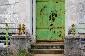 An old, weathered green door of a tomb with rust and peeling paint at Rookwood Necropolis, Sydney, NSW, Australia