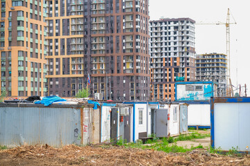 Moscow, Russia, 18.06.2025 Construction site with temporary worker cabins in the foreground and tall residential buildings, some still under construction behind.