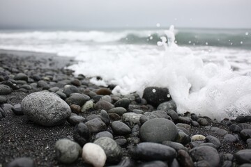 Foamy wave crashing on a dark pebbled beach