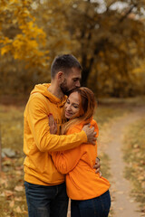 Fototapeta premium couple in love in yellow sweaters hugging in autumn park. autumn concept. autumn season. fall. husband and wife. groom and bride. guy and girl