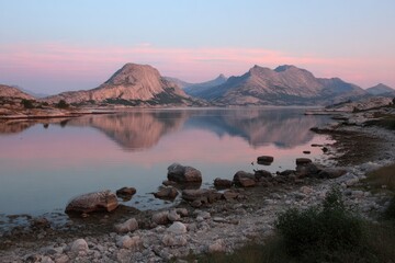 Calm lake reflecting pink sunrise mountains