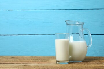 Glass of milk with jug on table