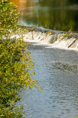 The cascading water of a small dam on a peaceful river. Peaceful river.