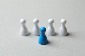 Obraz premium Blue pawn among white on gray background 