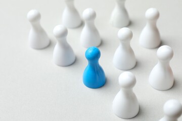 Blue pawn among white on the table. The concept of difference and uniqueness
