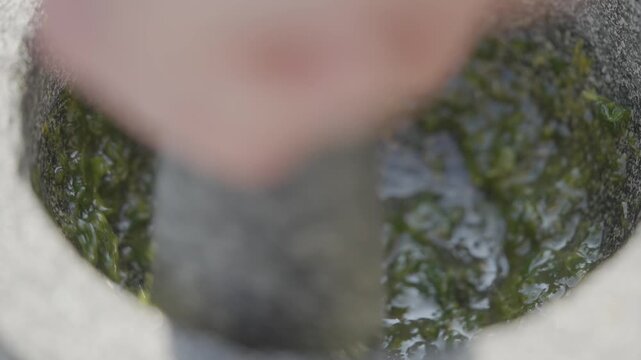 A person is standing in a puddle of water. The water is murky and green, and the person appears to be stirring it. The scene has a somewhat eerie or unsettling mood, as the water seems to be alive