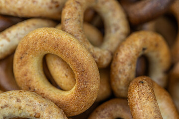 Freshly baked mini bagels on a dark background. Top view. Pretzels in the form of a ring close-up. Small bread circle biscuit. Bowls with different types of bagels.
