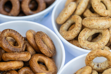 Freshly baked mini bagels on a dark background. Top view. Pretzels in the form of a ring close-up. Small bread circle biscuit. Bowls with different types of bagels.