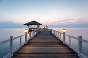 Obraz premium Beautiful pavilion and wooden bridge with empty sky and calm sea in background at travel attraction in Chonburi, Thailand. Scenic coastal view combines natural beauty with architectural engineering.