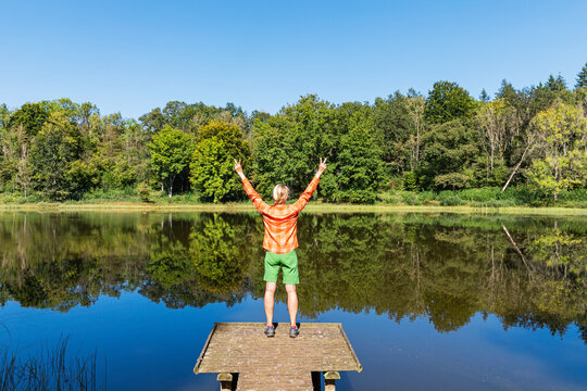 Woman cheering by Windsborn Crater Lake in Vulkan Eifel Germany