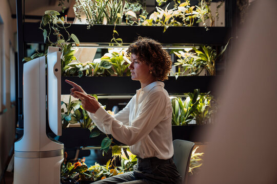 Woman working with robot and artificial intelligence in green office