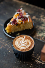 A slice of cake served with a cup of cappuccino featuring latte art, placed on a rustic wooden table. Cozy and inviting cafe scene, perfect for a relaxing coffee break, captured in natural light