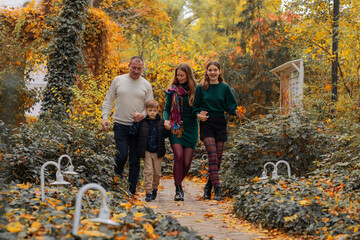 Big Happy Family: Mom, Dad and their two children, walking in autumn park along the path. autumn concept autumn season. fall. family day.