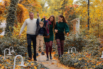 Big Happy Family: Mom, Dad and their two children, walking in autumn park along the path. autumn concept autumn season. fall. family day.