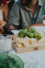 Fresh green grapes and cubes of cheese served on a white plate, perfect for a rustic, elegant gathering.