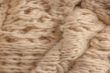 A fragment of beige knitted fabric, knitted from white sheep wool.