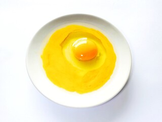 Fresh raw egg yolk in ceramic plate isolated on white background. Raw egg yolk. Cracked egg in a white bowl, ideal for culinary and kitchen themes. Top view.