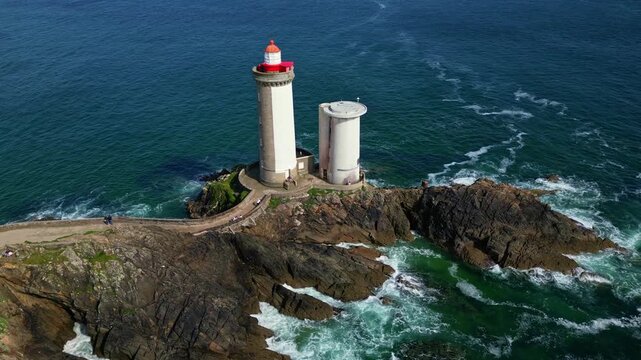 Drone tilt-down and lateral shot over Petit Minou lighthouse in Brittany, starting at the stone bridge and moving past the lighthouse along the cliffs and ocean waves. Plouzan&eacute;, France