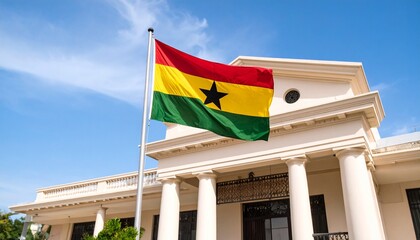 The national flag of Ghana with its black star waves proudly in front of a stately government building.