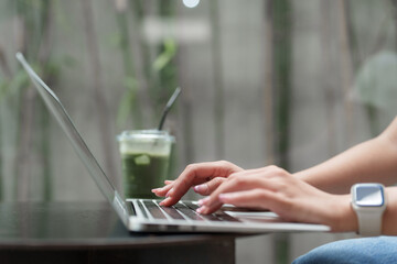Freelancer working on laptop with matcha latte in outdoor cafe