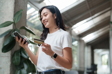 Young woman making online payment using credit card and smartphone