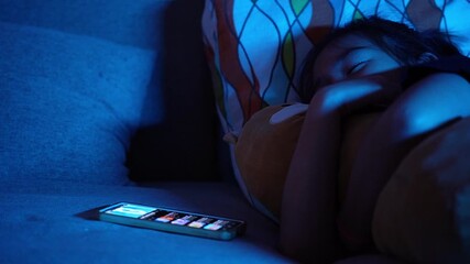 Asian child lying in bed using smartphone at night, screen light illuminating face, concept of screen time and digital addiction in kids - Powered by Adobe