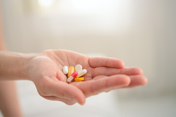 Pregnant female carefully examining pill before intake while touching her bump. Thoughtful health management during gestation period.