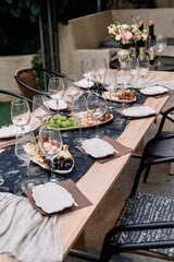 Elegant Outdoor Dining Setup with Beautiful Table Arrangements Featuring Wine Glasses, Gourmet Dishes, and Fresh Fruits for a Sophisticated Gathering