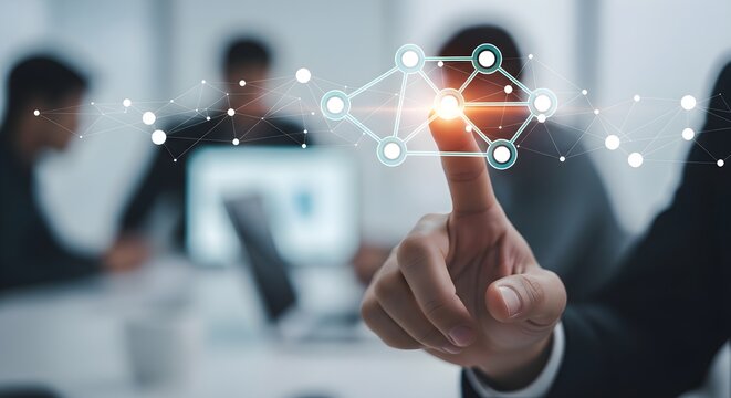 A businessman's finger interacts with a glowing network graphic, symbolizing connection and technology, with colleagues blurred in the background.