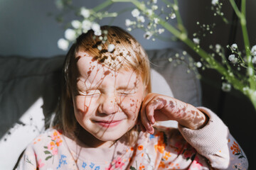 Beautiful little girl smiling and squinting in sunlight. Portrait of dreamy playful child preschool age.