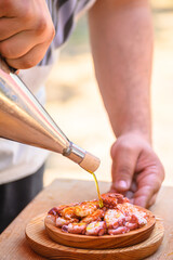 Preparing Pulpo a Feira on a wooden plate, traditional GALICIA cuisine.