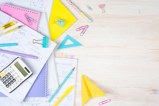 Mathematical formulas written in notebooks, multicolor stationery and calculator on wooden desk top view with copy space on right side