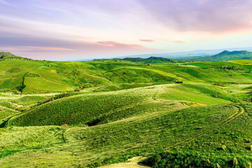 Obraz premium green grassland landscape of spring season beautiful evening among mountains and hills. Rustic village in green spring valley.