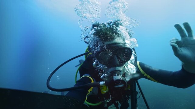Scuba diver doing safety OK underwater sign, enjoying deep diving in the ocean