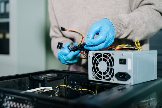 Technician in gloves handling power supply and cables during desktop PC assembly. Perfect for themes like computer repair, PSU install, and hardware build safety.